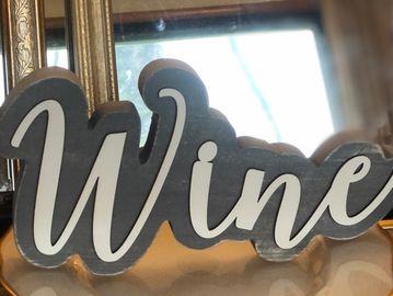 A decorative sign with the word 'Wine' in elegant script.