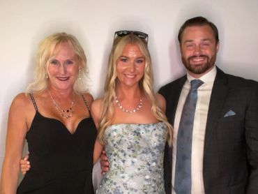 Three people dressed formally, smiling for a photo.