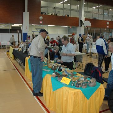 Wood carving show with two people talking over a table with carvings displayed.