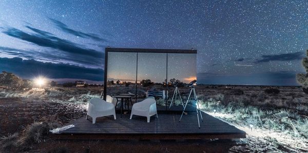 Mirrored invisible tiny home surrounded by nighttime starlit sky.