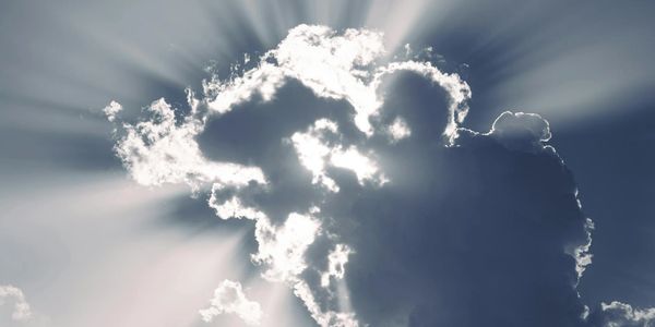 Sunlight beams burst dramatically from behind dark clouds in the sky.