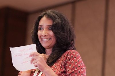 Woman smiling and holding a piece of paper on stage.
