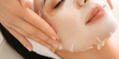 Person receiving a facial sheet mask treatment at a spa.