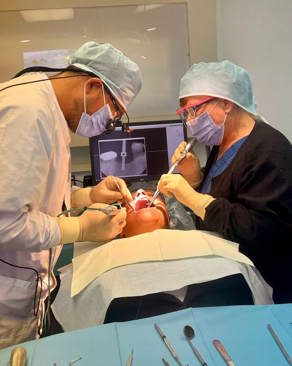 Two dentists performing a dental procedure on a patient.