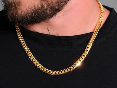 Close-up of a person wearing a shiny gold chain necklace with a black shirt.