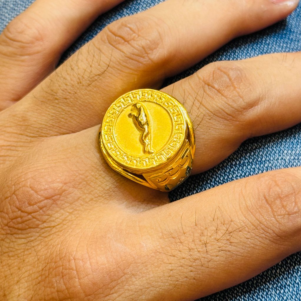Close-up of a hand wearing a gold ring with a horse design.