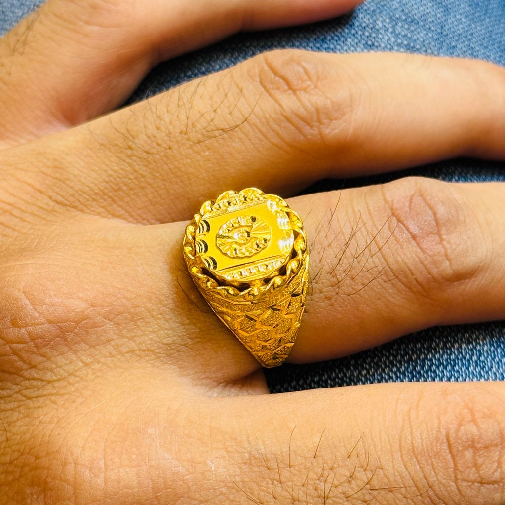 Hand wearing a detailed gold ring with intricate patterns.