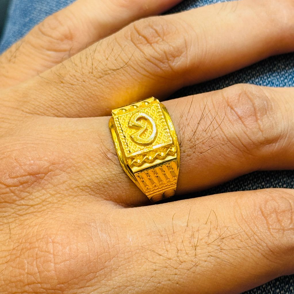 Gold ring with intricate design on a finger.