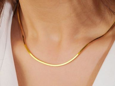 Close-up of a gold chain necklace on a person's neck.