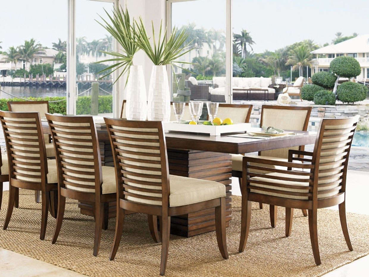 Elegant wooden dining set with cushioned chairs in a bright room overlooking water.