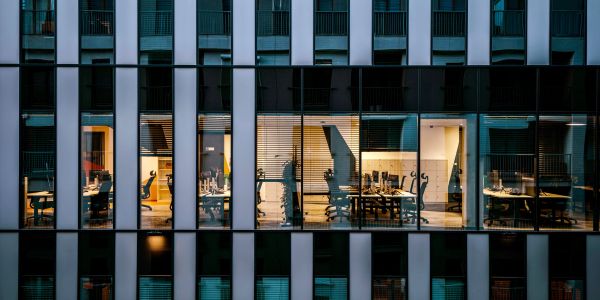Modern office building facade with illuminated workspaces at dusk.