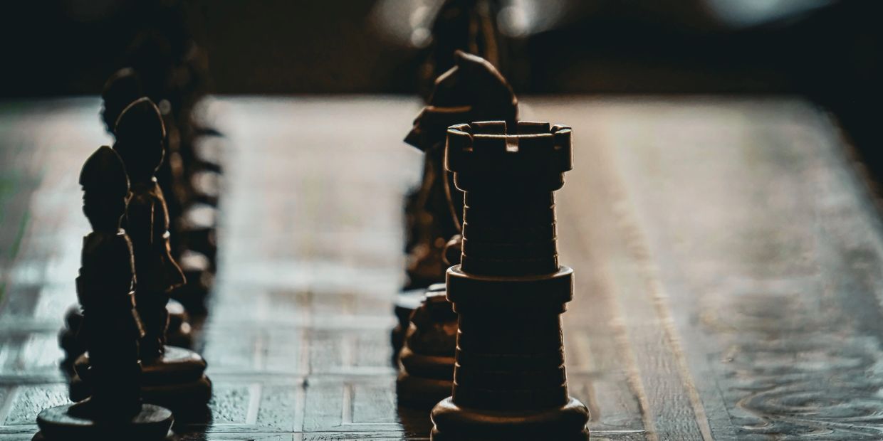Close-up of chess pieces on a board with dim lighting.