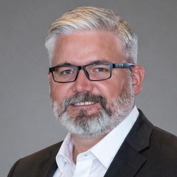 Portrait of a middle-aged man with gray hair, beard, and glasses.