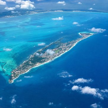 Aerial view of a narrow island surrounded by vibrant blue ocean waters.