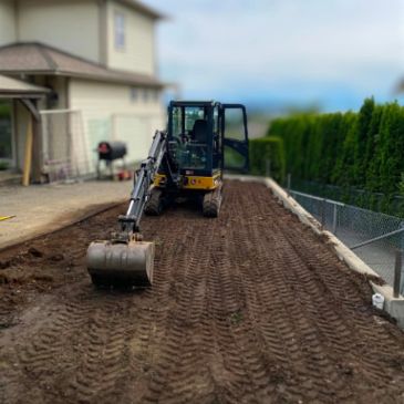 Small excavator on freshly dug soil near a house.