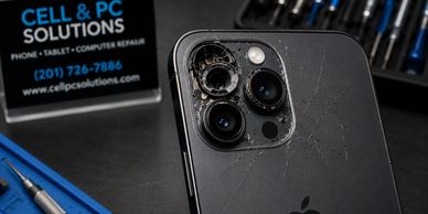 Broken iPhone camera lens with repair tools.