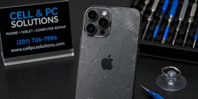Cracked iPhone back with repair tools and service sign.