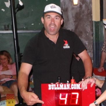 BullMan pointing at the champion bull ride time displayed on the front of the bull controller with the winning rider proudly standing by