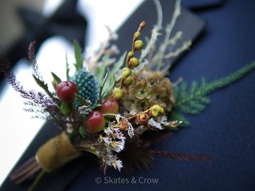 Close-up of a rustic boutonniere with dried flowers and berries.