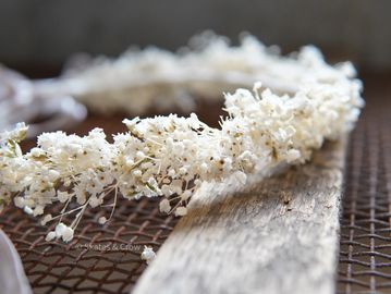 Close-up of delicate white baby's breath flowers on rustic wood and mesh.