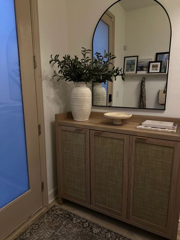 Minimalist entryway with wooden cabinet and large mirror.
