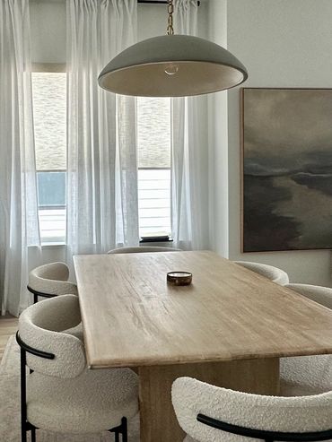Minimalist dining area with wooden table and white chairs.