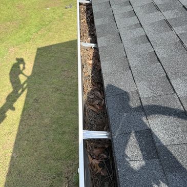Professional gutter cleaning in Pensacola, FL with leaves and debris being removed.