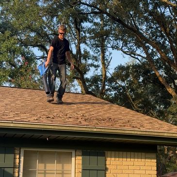 Technician providing gutter cleaning service in Pensacola to prevent water damage.