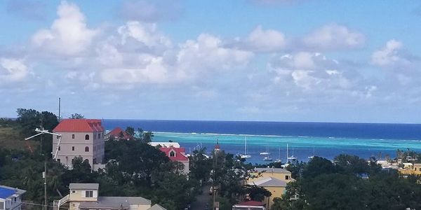 Coastal town with colorful buildings and boats on turquoise water under a blue sky.
