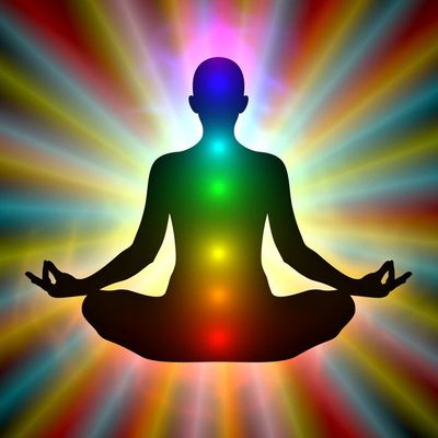 Silhouette of a meditating person with chakras shining