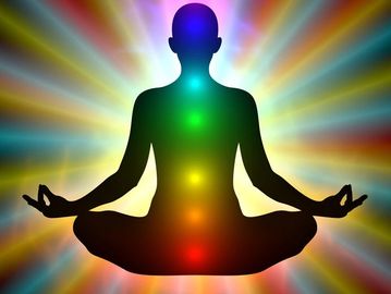 A person outline in the lotus position with chakras shining