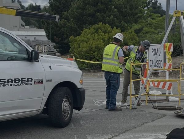 SABER Technologies truck and two individuals wearing hard hats installing outside plant cabling