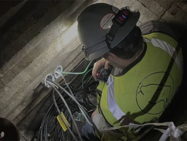 One individual wearing a hard hat working on outside plant cabling