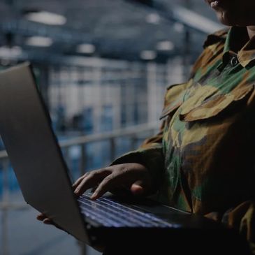 Military personnel in a data center working on a laptop