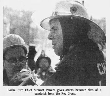 Fire chief Stewart Powers gives orders while eating a sandwich.