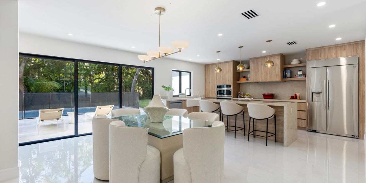 Modern kitchen with glass dining table and sliding door to outdoor pool.