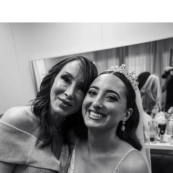 A joyful bride and her mother share a loving moment in black and white.