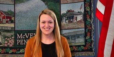 Picture of Brooke Knable in front of the McVeytown Blanket and American Flag to the right. 