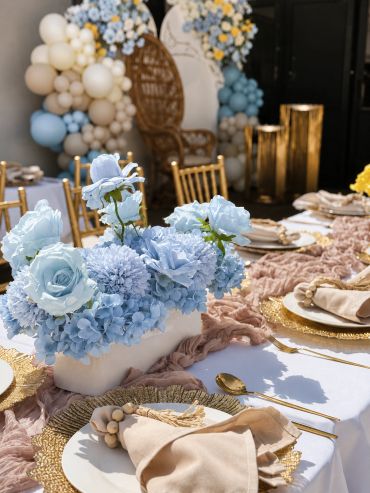 Elegant table setting with blue flower centerpiece and gold accents.