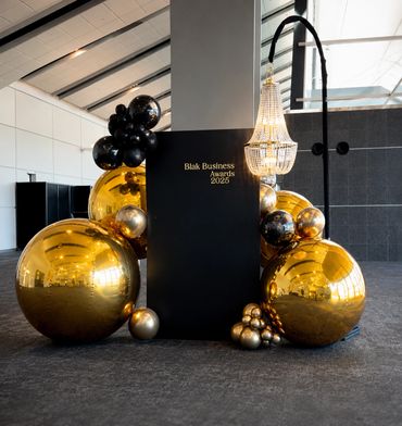 Decorative golden and black balloon arrangement for Blak Business Awards 2025.