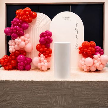 Colorful balloon arrangement for an eighteenth birthday celebration with a white podium.