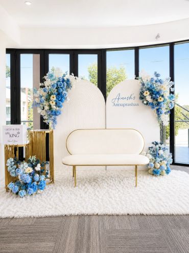 Elegant white and blue floral event setup with modern seating and gold accents.