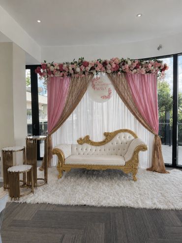 Elegant white and gold sofa under pink and gold floral draped canopy.
