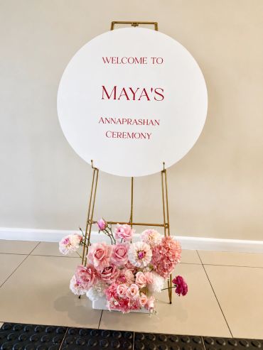 Welcome sign for Maya's Annaprashan ceremony with pink floral decoration.