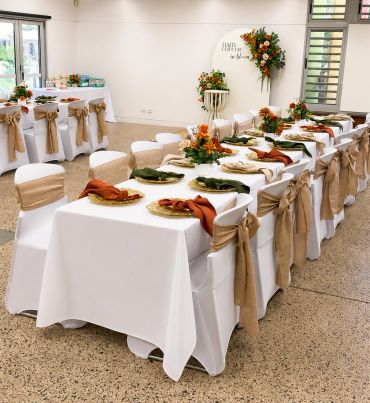 Elegant banquet setup with white tablecloths and autumn-themed decorations.