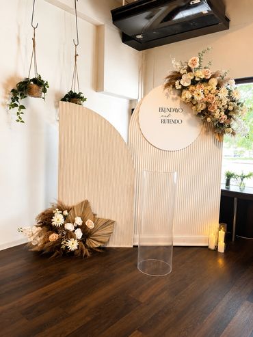 Elegant floral wedding backdrop with neutral tones and hanging plants.