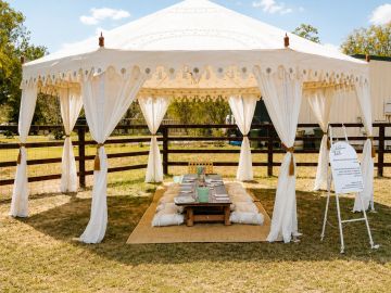 Elegant outdoor tent setup with low dining table and cushions on grass.
