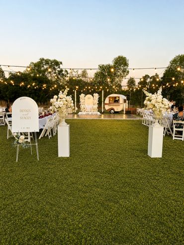 Elegant outdoor wedding setup with floral arrangements and string lights.