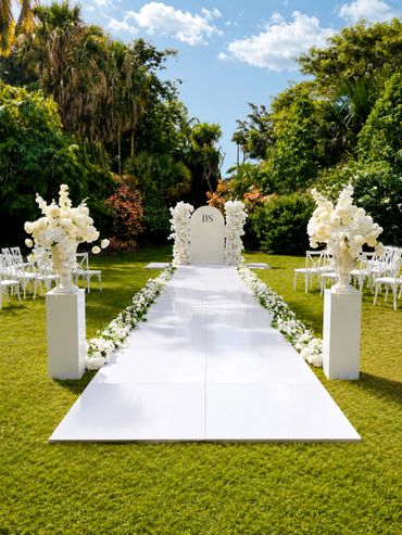 Elegant outdoor wedding aisle decorated with white flowers and greenery.