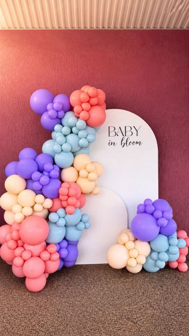 Colorful balloon arrangement with a "Baby in bloom" sign for a celebration.